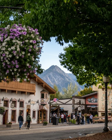 Charming mountain town street with hanging flower baskets and a mountain peak in the background