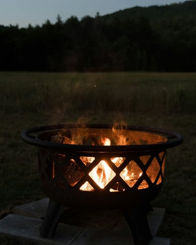 Fire pit glowing at dusk with mountain silhouette in the background