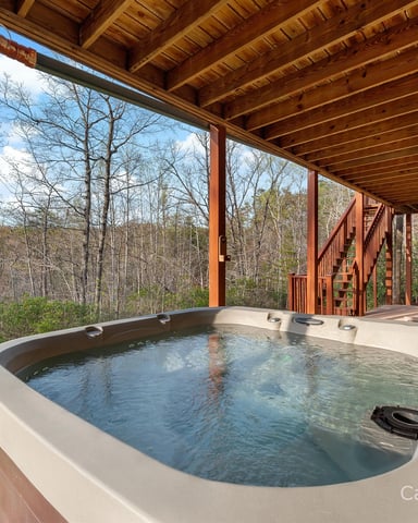 Two turquoise kayaks hanging from wooden pergola structure with Adirondack chair below, surrounded by green forest canopy